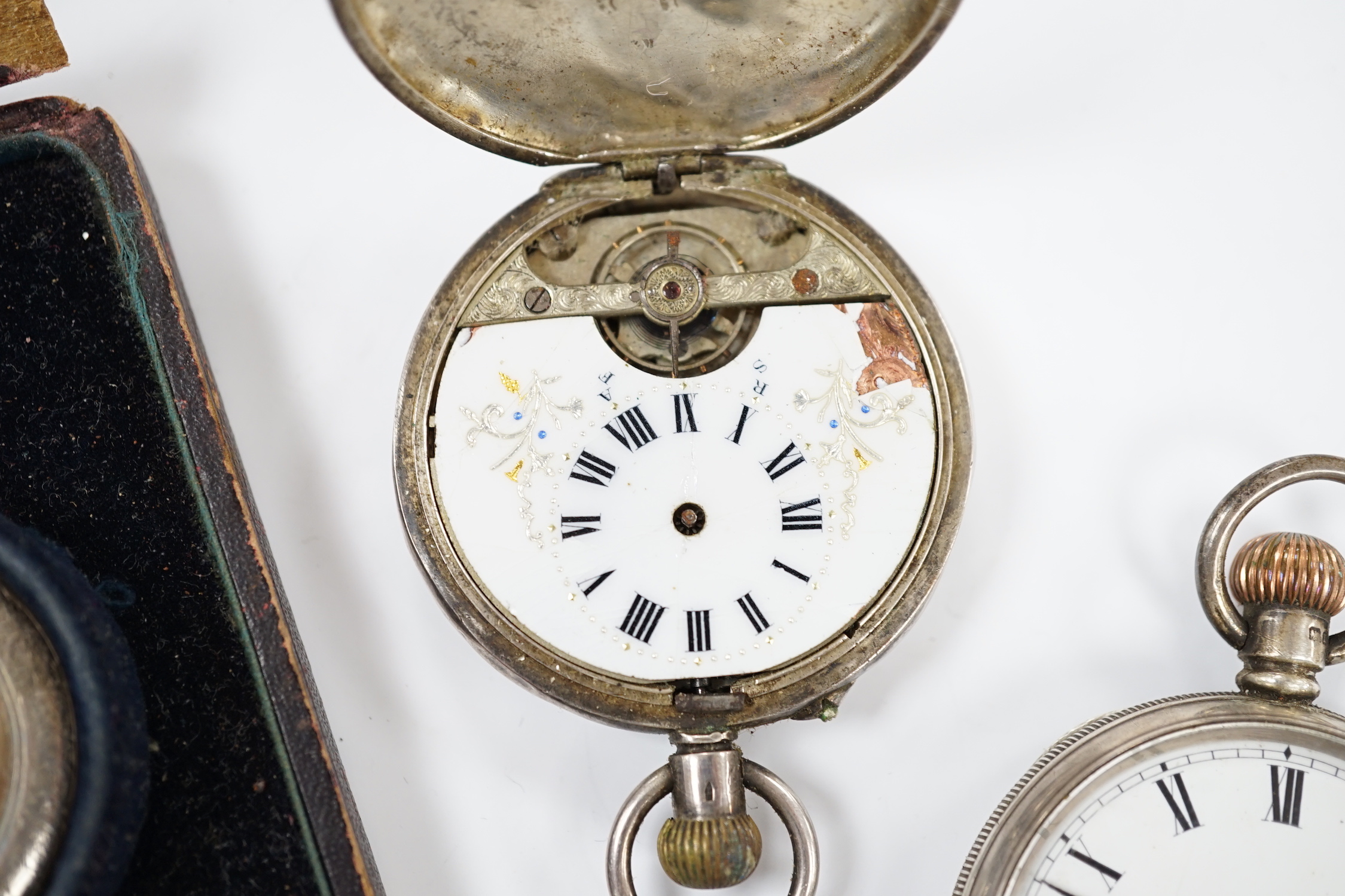 Three silver pocket watches and a travel timepiece.